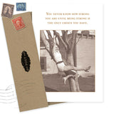 The Strong Encouragement Card by Shannon Martin Design features a vintage image of a smiling woman in shorts and tank top hanging from a tree and the message: "You never know how strong you are until being strong is the only choice you have." Envelope included. Made in USA.