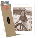 The Joy Be Compass Birthday Card by Shannon Martin Design features a sepia-toned photo of a smiling woman in a sailor hat, the phrase "Let joy be your compass," and includes a brown envelope with vintage stamps. Made from recycled paper.
