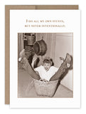 A vintage photo from Shannon Martin Design's collection, featuring a woman in a basket with her legs up and a pot precariously hanging above, captures spontaneous humor. The text reads, "I do all my own stunts, but never intentionally." This image is part of the award-winning "My Own Stunts Birthday Card" line known for its timeless style.