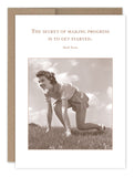 A sepia-toned vintage photo shows a woman crouched on the grass, poised to sprint, with an inspiring quote above: "The secret of making progress is to get started." - Mark Twain. The image is set against a brown recycled paper card for an eco-friendly touch, aptly named the Get Started Encouragement Card by Shannon Martin Design.