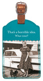 The Shannon Martin Design "What Time? Luggage Tag" displays a vintage-style image of a woman in a patterned dress standing next to a classic car, accompanied by her small dog. The accompanying text reads, "That's a horrible idea. What time?" This tag boasts an elegant leatherette finish complemented by a copper metallic strap at the top.