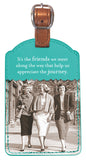 The "Friends We Meet Luggage Tag" by Shannon Martin Design elegantly showcases a vintage photo of three women walking arm in arm, smiling, on a teal leatherette surface. It includes the heartfelt quote, "It's the friends we meet along the way that help us appreciate the journey," and is complemented with a sturdy brown leather strap.