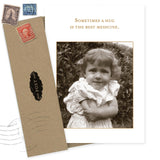 The Hug Best Medicine Get Well Card by Shannon Martin Design features a sepia photo of a curly-haired child hugging herself with the words "Sometimes a hug is the best medicine." Made in USA, includes brown envelope and vintage stamps.