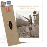 The Train Of Thought Birthday Card by Shannon Martin Design features a vintage-style woman in 1950s attire by train tracks with a suitcase, hitchhiking. The card reads: "I'm afraid my train of thought has left the station." Ideal for a belated birthday!.