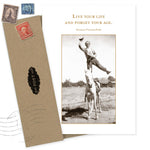 The Live Your Life Birthday Card by Shannon Martin Design features a sepia vintage photo of a man balancing on one leg atop a horse and the quote “Live your life and forget your age.” Includes envelope and vintage stamps.