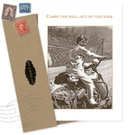 The Carpe Diem Birthday Card by Shannon Martin Design features a sepia photo of a smiling woman on a vintage motorcycle, a brown envelope with old postage stamps, and gold "Carpe the hell out of this diem." text, printed on recycled paper.