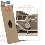 The Buy The Shoes Birthday Card by Shannon Martin Design features a sepia photo of a smiling woman in a dress and heels by a classic car, with the quote "Life is short. Buy the damn shoes." Includes an envelope with vintage stamps and recycled paper.