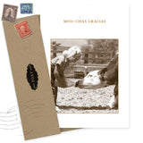 The Gracias Thank You Card by Shannon Martin Design features "MOO-CHAS GRACIAS" above a sepia girl feeding a calf. Made in USA, it includes a brown envelope with vintage stamps and a POST label.