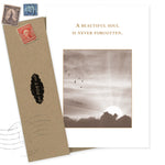 The Beautiful Soul Sympathy Card by Shannon Martin Design features sepia birds near a cloudy sun, with "A beautiful soul is never forgotten," and includes a recycled brown envelope decorated with stamps and a black POST label.