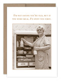 This nostalgic sepia-toned "Not Saying Birthday Card" by Shannon Martin Design features an elderly woman reaching into a vintage refrigerator with a milk bottle in hand. The humorous caption reads, "I'm not saying you're old, but if you were milk, I'd sniff you first." Made from recycled paper and crafted in the USA.