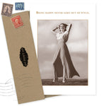 The Being Happy Birthday Card by Shannon Martin Design features a smiling woman in high-waisted pants and a blouse on grass. Inspired by vintage photos, it comes with a retro-stamped envelope made from recycled paper.