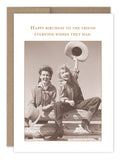 Introducing the "Hats Off Birthday Card" by Shannon Martin Design. This vintage-style card showcases two people on a fence, one waving a cowboy hat, and is printed on recycled paper. The card conveys the message, "Happy birthday to the friend everyone wishes they had," and comes with Shannon's signature envelope for an added touch of charm.