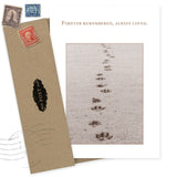 The Forever Remembered Pet Sympathy Card by Shannon Martin Design, made in the USA, features paw prints in sand with "Forever remembered, always loved," and comes with a brown envelope decorated with vintage stamps and a black POST label.