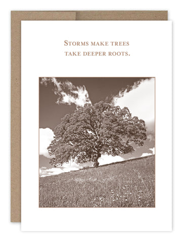 The Deeper Roots Encouragement Card by Shannon Martin Design features a sepia-toned image of a large tree in a field under a partly cloudy sky, with the text Storms make trees take deeper roots. Its crafted from recycled paper and includes a matching kraft envelope for a rustic look.