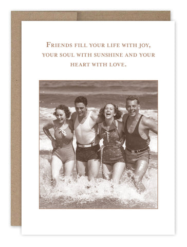 The Shannon Martin Design Friends Fill Your Life Birthday Card features a sepia-toned image of friends in swimsuits embracing in the ocean, with the vintage-style text: Friends fill your life with joy, your soul with sunshine and your heart with love. Ideal for a heartfelt birthday celebration.