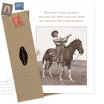 The "You Don't Stop Laughing Birthday Card" by Shannon Martin Design features a sepia cowboy playing guitar on horseback, alongside the quote: "You don’t stop laughing because you grow old; you grow old because you stop laughing," plus a vintage-style envelope.