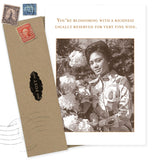 The Blossoming Birthday Card by Shannon Martin Design features a sepia photo of a woman with flowers and the message, "You’re blossoming with a richness usually reserved for very fine wine." Made in the USA. Envelope and vintage stamps included.