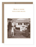 A smiling couple stands with a real estate agent as a "Sold" sign is placed in front of their new home. The Where Your Story Begins New Home Card by Shannon Martin Design features the message: Home is where your story begins.