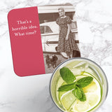 The Shannon Martin Design "What Time Coaster" is a retro cork-backed coaster with a vintage woman, dog, and car photo. It reads, “That’s a horrible idea. What time?” Heat and water resistant, it's shown beside lemon water on marble.
