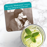 The Moderation Coaster by Shannon Martin Design features a retro image of a woman enjoying a beer, captioned “Who is this ‘Moderation’ everyone keeps telling me to drink with?” and sits alongside a glass of lemonade on marble.