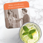 The We're All Crazy Coaster by Shannon Martin Design, a retro cork-backed coaster with a vintage photo and the quote “Relax, we’re all crazy. It’s not a competition,” is shown beside a refreshing citrus drink with mint and ice.