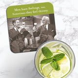 The Men Have Feelings Coaster by Shannon Martin Design features a retro photo of two men in suits raising drinks with the caption, "Men have feelings, too. Sometimes they feel thirsty," shown next to a glass of lemonade on marble.