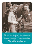 A woman in Western attire and a cowboy hat stands smiling beside a horse in a vintage-style image. Below, on a teal panel, is the text: If standing up for yourself burns a bridge, I have matches in my lockers. We ride at dawn. Product: We Ride At Dawn Magnet by Shannon Martin Design.