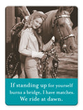 A smiling woman in a cowboy hat stands by a saddled horse, holding its reins. Text: If standing up for yourself burns a bridge, I have matches. We ride at dawn. We Ride At Dawn Magnet by Shannon Martin Design—perfect quirky gift!.