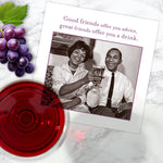 The Offer You Advice Napkin by Shannon Martin Design is displayed on a marble surface with grapes, red wine, and a card showing friends clinking glasses and the message: Good friends offer you advice, great friends offer you a drink.