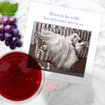 The “Born To Be Wild Napkin” by Shannon Martin Design features the text “Born to be wild, but only until 9PM or so” above a vintage photo of a woman in a frilly dress lounging with grapes and wine—a fun touch for any stylish night in.
