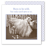 A woman in a frilly gown lounges on a striped couch, shoes off, looking tired. Text above: Born to be wild, but only until 9PM or so—just like the "Born To Be Wild" napkin by Shannon Martin Design.
