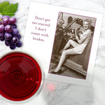 A Shannon Martin Design "Don't Get Started Napkin" rests on a marble surface beside grapes, red wine, and a card depicting a smiling woman in vintage attire in a classic car with the text, "Don’t get me started. I don’t come with brakes.