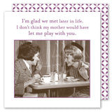 Two women at a vintage cafe laugh over coffee, holding Glad We Met Napkins by Shannon Martin Design. Above them: "I’m glad we met later in life. I don’t think my mother would have let me play with you.
