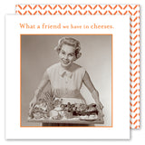 A smiling woman in a vintage dress holds a tray of cheese and snacks under the text "What a friend we have in cheeses." The orange and white border of the What A Friend Napkin by Shannon Martin Design matches classic beverage napkins.