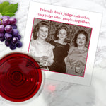 A vintage photo of three women with drinks features on the Shannon Martin Design "Friends Don't Judge Napkin," printed with the quote: Friends don't judge each other, they judge other people...together. Biodegradable, FSC-certified.