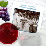 On a marble surface, Shannon Martin Design's Celebrate Everything Napkin sits beside a greeting card that reads "Until further notice, celebrate everything!" with a vintage photo, plus grapes and a glass of red wine.