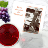 The "What Time? Napkin" by Shannon Martin Design features a vintage photo of a woman in a dress with her dog by a car and the phrase “That’s a horrible idea. What time?” Shown with party napkins, grapes, and red wine on marble.