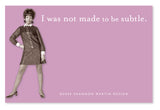 A woman in a retro dress and funky earrings poses confidently with her hands on her hips. On the pink background, you can see the humorous text, "I was not made to be subtle," from Shannon Martin Design's Not Subtle Sticky Note, a bold statement reminiscent of colorful individuality crafted in the USA.