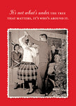 A vintage photo on the "Not What's Under Holiday Card" by Shannon Martin Design shows a couple dancing joyfully amidst smiling guests in a festive setting, with a beautifully decorated Christmas tree standing nearby. The message printed on recycled paper says, "It's not what's under the tree that matters; it's who's around it.