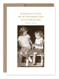 The "A Sister Is Birthday Card" by Shannon Martin Design features a sepia-toned photograph of two young girls in vintage 1950s attire, smiling at each other as they sit on a bench. Accompanying the image is the heartfelt quote: "A sister is a little bit of childhood that can never be lost." The nostalgic feel of the picture evokes the charm of being tucked away in an old kraft envelope.