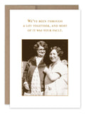 Two women smiling and standing close, evoking a vintage photo vibe. The text above reads: "We've been through a lot together, and most of it was your fault." The plain background enhances the Your Fault Friendship Card from Shannon Martin Design, perfectly paired with its kraft envelope.