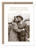 A charming vintage photo of a couple in formal wear graces the front of "The Best Thing Anniversary Card" by Shannon Martin Design, printed elegantly on recycled paper. The card features the heartfelt Audrey Hepburn quote, "The best thing to hold onto in life is each other," making it perfect for conveying your warm Happy Anniversary wishes.