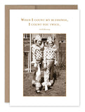 The Count Twice Thank You Card by Shannon Martin Design showcases a sepia-toned image of two children in checkered costumes outdoors, printed on recycled paper and made in the USA. The text "When I count my blessings, I count you twice. Irish Blessing" appears above them. This vintage-inspired card features a brown border and a blank background.