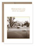 A delightful greeting card from Shannon Martin Design features a vintage black-and-white photo of a smiling woman in a convertible. The card, made in the USA, cheekily asks, "Does running late count as cardio?" Crafted on recycled paper, the Count As Cardio Birthday Card adds a charming touch on an eco-friendly canvas.