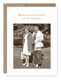 The "Too Young Birthday Card" by Shannon Martin Design features a retro-inspired image of two elderly women joyfully smiling outdoors, wearing long skirts and shawls, with one carrying a handbag. Above them is the playful message: "We're much too young to be this old." This card is printed on recycled paper and proudly made in the USA.