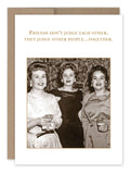 A vintage black and white photo featuring three smiling women in elegant dresses, each holding a drink. The text above them reads, "Friends don‚Äôt judge each other, they judge other people...together." This image is part of the award-winning collection by Shannon Martin Design and is featured on the Judge Other People Birthday Card, made with FSC-certified paper and paired with a brown envelope.