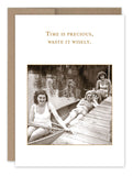 A vintage-style image featuring three women enjoying a leisurely moment by a wooden dock, printed on textured recycled paper. Two women relax in a canoe, while the third sits on the dock. The card, titled "Time Precious What A Hoot," bears the words "Time is precious, waste it wisely" and is crafted by Shannon Martin Design.