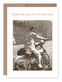 A vintage black and white photo of a person joyfully riding a motorcycle on a rural road is printed on recycled paper in the Carpe Diem Birthday Card from Shannon Martin Design. The words "Carpe the hell out of this diem" infuse the image with timeless charm, perfectly capturing its spirit.