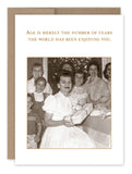 The "Enjoying You Birthday Card" by Shannon Martin Design is a vintage photo greeting card made in the USA, featuring a group of joyful people gathered around a seated woman holding a gift. Printed on recycled paper, it expresses the sentiment, "Age is merely the number of years the world has been enjoying you," with timeless elegance.