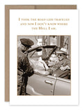 A sepia-toned image of a smiling couple in a convertible asking for directions from a police officer, reminiscent of vintage photographs. The caption above reads: "I took the road less traveled and now I don‚Äôt know where the hell I am." This is from the Road Less Traveled Birthday Card by Shannon Martin Design.